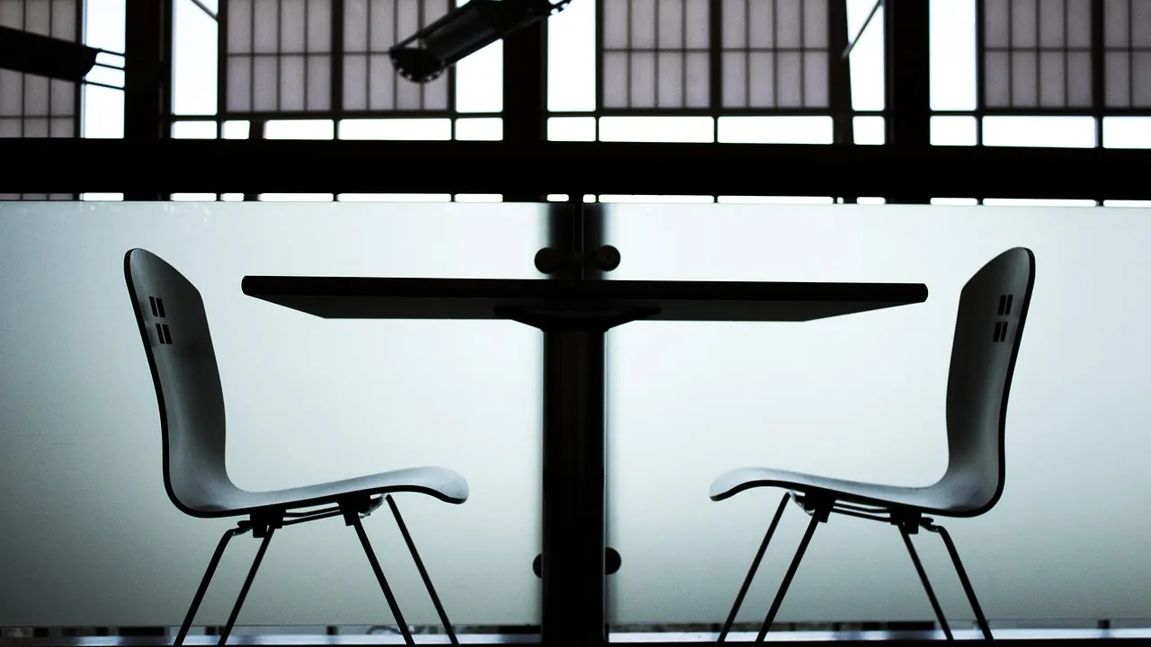 Deux chaises se faisant face de part et d'autre d'une table, à contre-jour