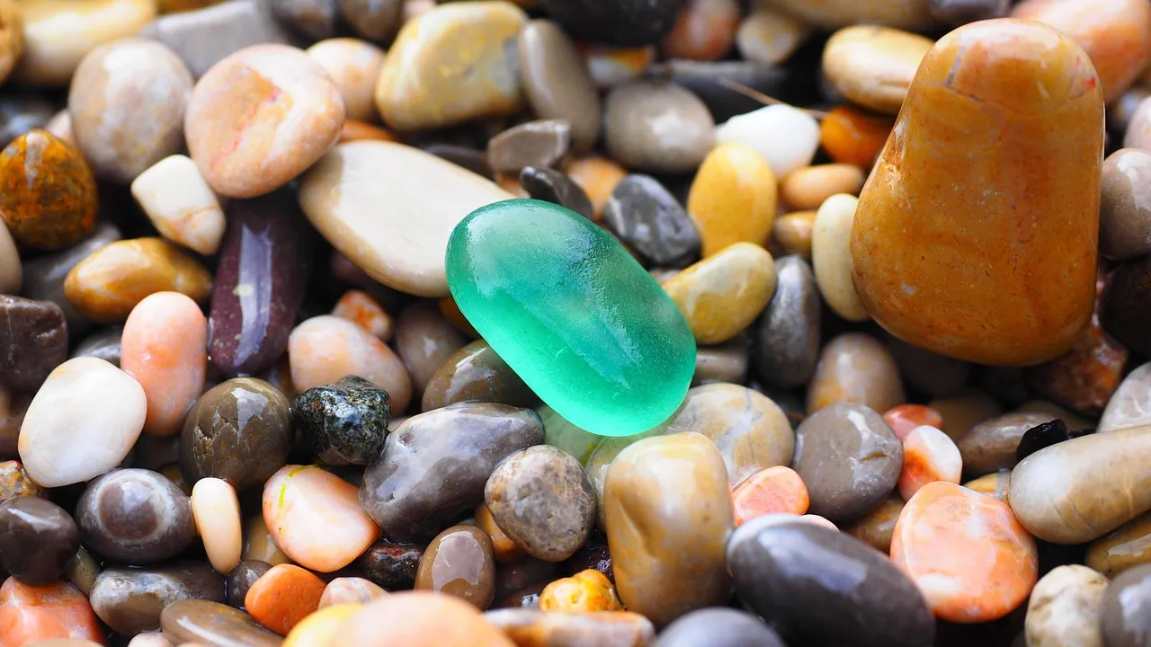 Un galet de verre vert translucide au milieu d'un lit de cailloux opaques