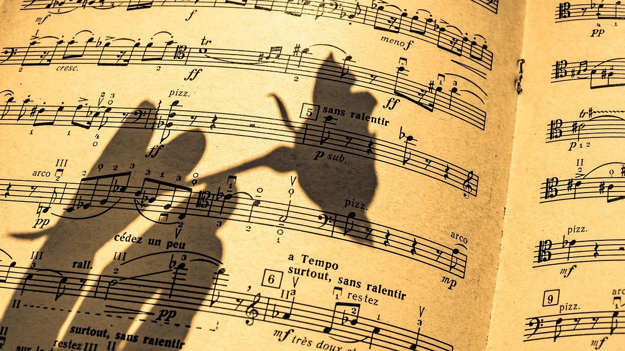 Une partition d'orchestre traversée par l'ombre des mains du chef