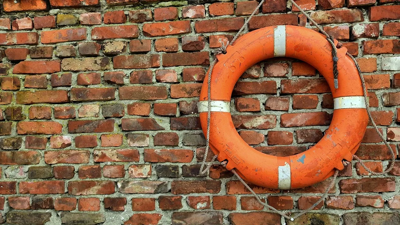 Une bouée de sauvetage orange accrochée à un mur de brique